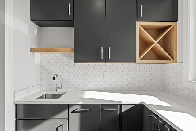 kitchen featuring backsplash, light stone countertops, and sink