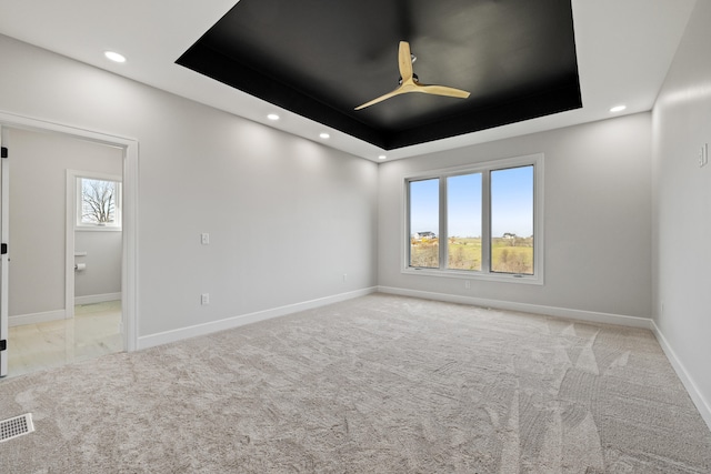 carpeted empty room with a tray ceiling and ceiling fan