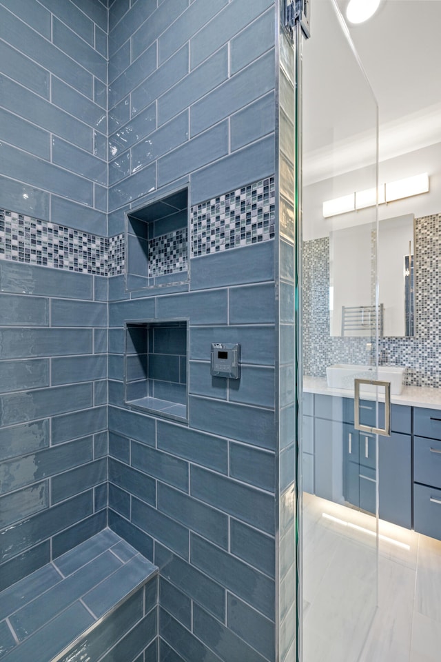 bathroom with tasteful backsplash, vanity, ornamental molding, and tiled shower