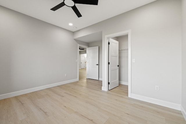 unfurnished bedroom with ceiling fan, light hardwood / wood-style floors, a walk in closet, and a closet