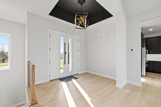 foyer entrance with a tray ceiling and light hardwood / wood-style flooring