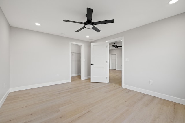 unfurnished bedroom with ceiling fan, light hardwood / wood-style floors, a spacious closet, and a closet