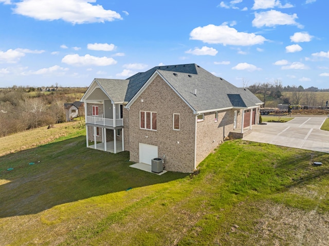 rear view of house with a yard, a balcony, a garage, and central AC unit