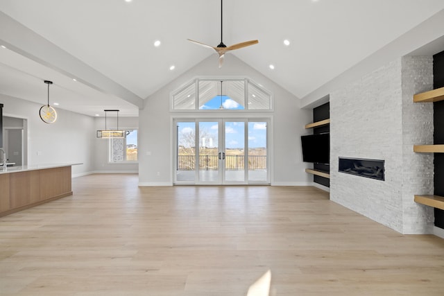 unfurnished living room with ceiling fan, sink, light hardwood / wood-style flooring, built in features, and a fireplace