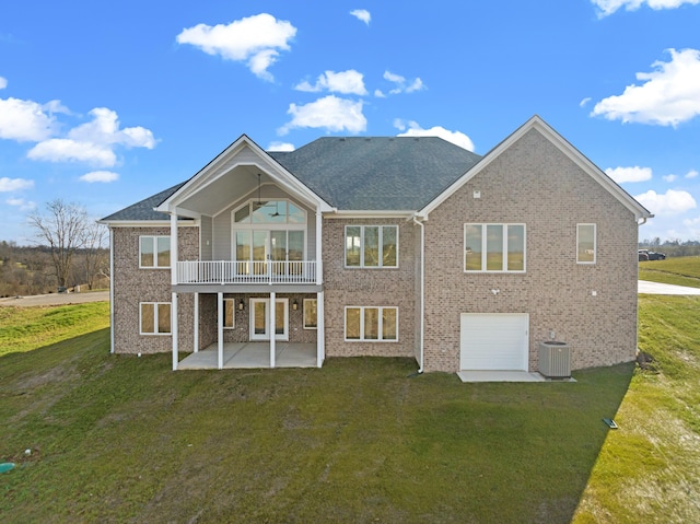 rear view of property with a lawn, a balcony, central AC unit, a garage, and a patio area