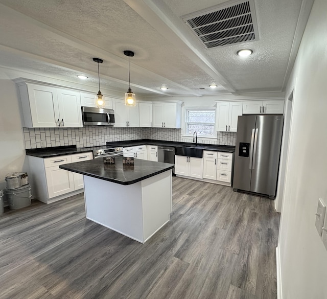 kitchen with appliances with stainless steel finishes, white cabinetry, and pendant lighting