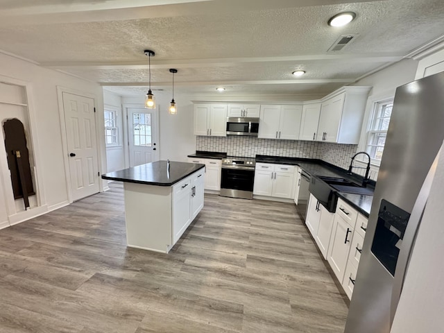 kitchen with tasteful backsplash, stainless steel appliances, sink, decorative light fixtures, and white cabinetry