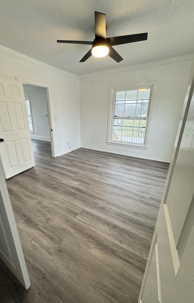 spare room with a healthy amount of sunlight, crown molding, and dark wood-type flooring