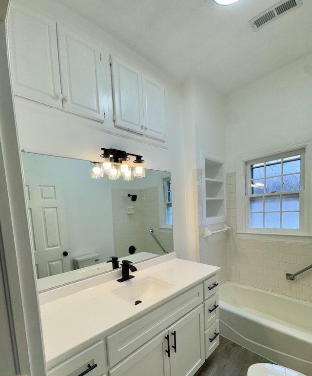 bathroom featuring vanity, toilet, wood-type flooring, and a washtub