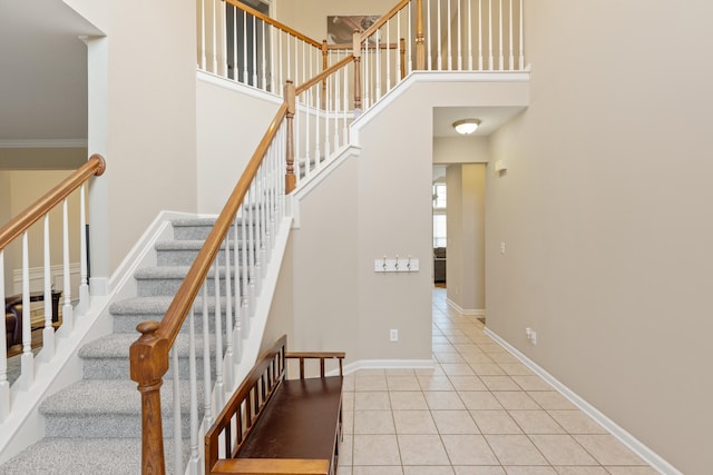 stairway with crown molding, tile patterned flooring, and a towering ceiling