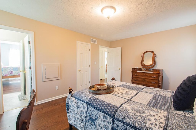 bedroom with dark hardwood / wood-style flooring and a textured ceiling