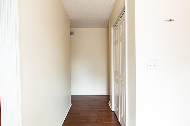 hallway featuring dark hardwood / wood-style flooring and a textured ceiling