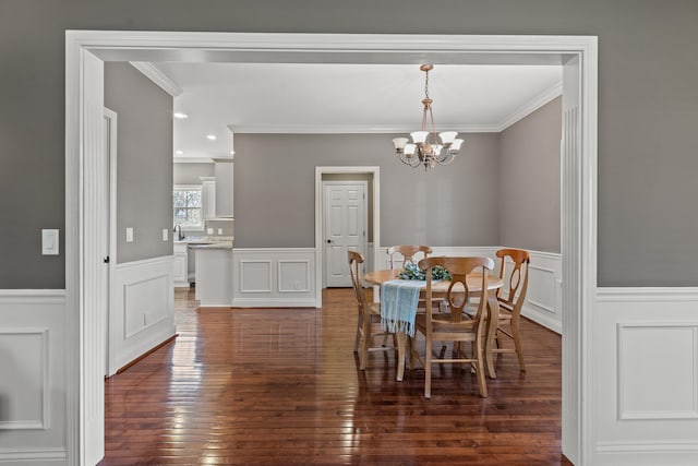 dining area with a notable chandelier, crown molding, and dark wood-type flooring