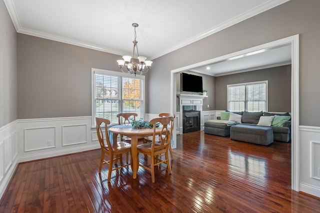 dining room with a notable chandelier, ornamental molding, and dark wood-type flooring