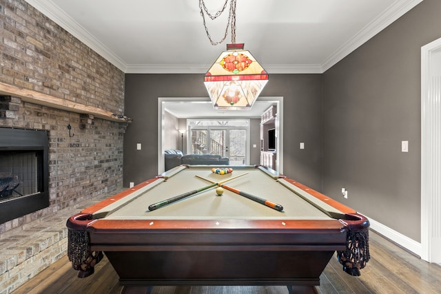 recreation room with wood-type flooring, ornamental molding, billiards, and a brick fireplace