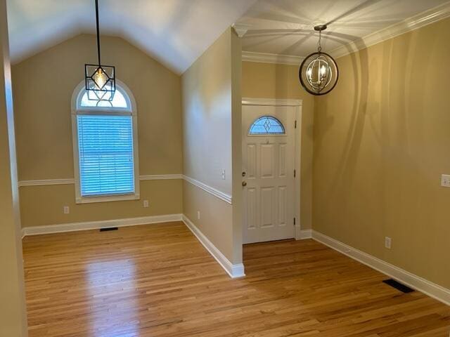 entryway featuring light hardwood / wood-style flooring, a chandelier, vaulted ceiling, and ornamental molding