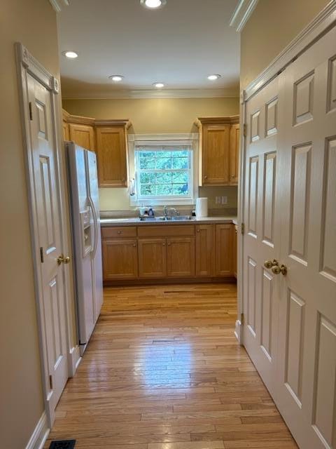 kitchen featuring light wood-type flooring, white fridge with ice dispenser, and ornamental molding