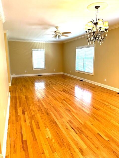 spare room featuring ceiling fan with notable chandelier, light hardwood / wood-style floors, plenty of natural light, and crown molding