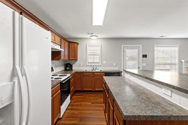 kitchen with dark hardwood / wood-style flooring, white appliances, and sink