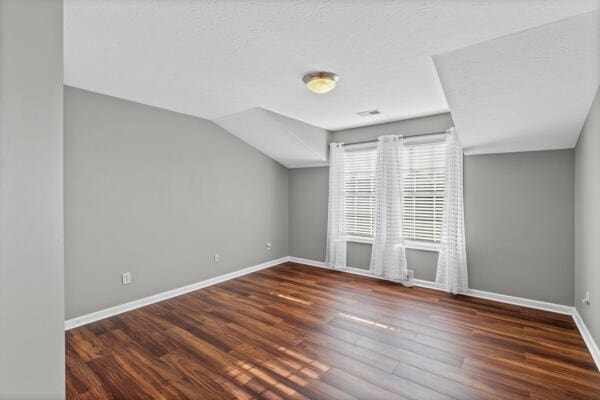 bonus room with lofted ceiling and dark wood-type flooring