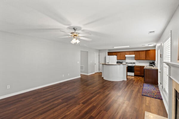 kitchen featuring ceiling fan, a center island, dark wood-type flooring, and white appliances