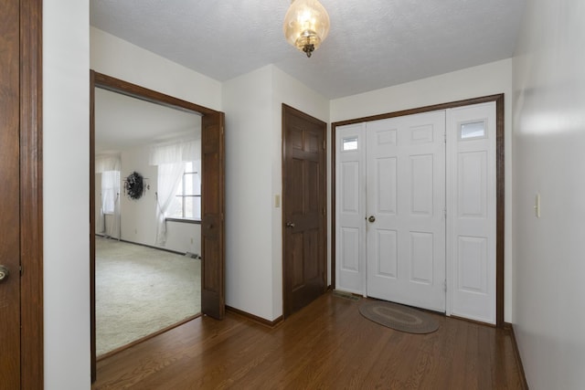 foyer entrance featuring a textured ceiling and dark wood-type flooring