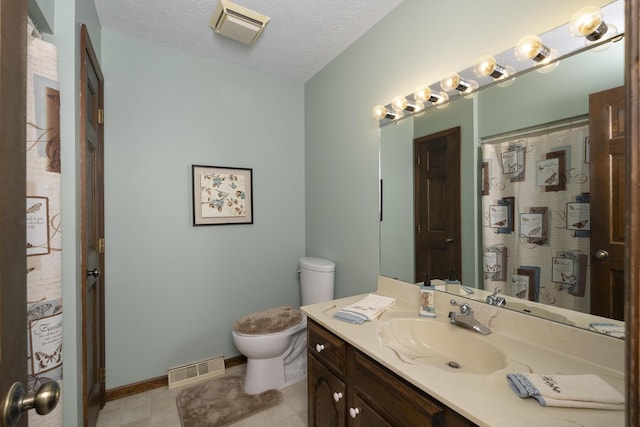 bathroom featuring vanity, toilet, and a textured ceiling