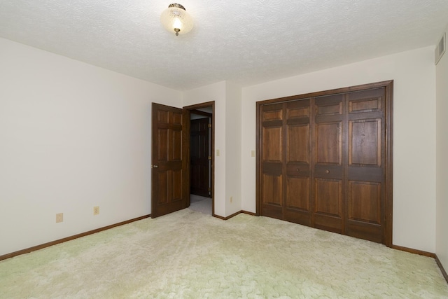 unfurnished bedroom with light colored carpet, a textured ceiling, and a closet