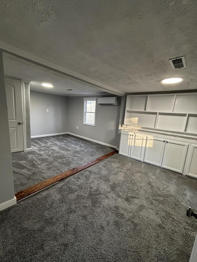 basement featuring an AC wall unit, dark carpet, and a textured ceiling