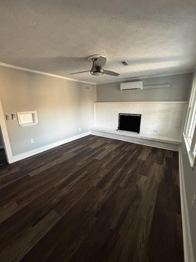 unfurnished living room featuring ceiling fan, a wall mounted air conditioner, dark hardwood / wood-style floors, a textured ceiling, and a fireplace