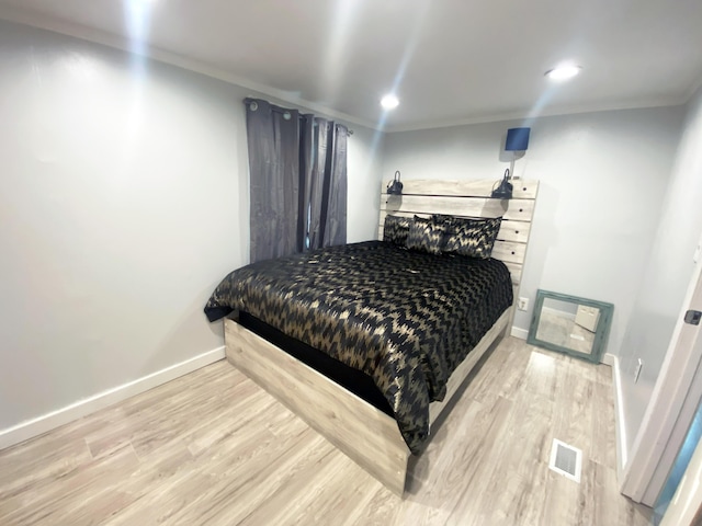 bedroom with light wood-type flooring and ornamental molding