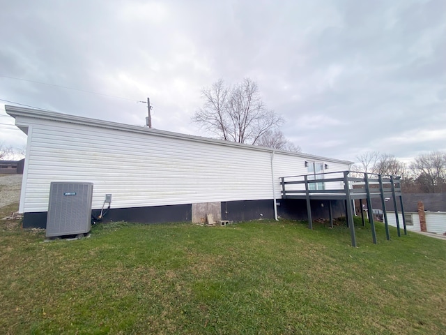 view of side of property featuring central AC unit, a deck, and a yard