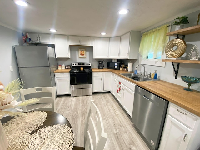 kitchen featuring wood counters, appliances with stainless steel finishes, sink, white cabinets, and light hardwood / wood-style floors