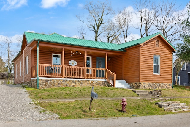 view of front of property with metal roof, a porch, log veneer siding, and driveway