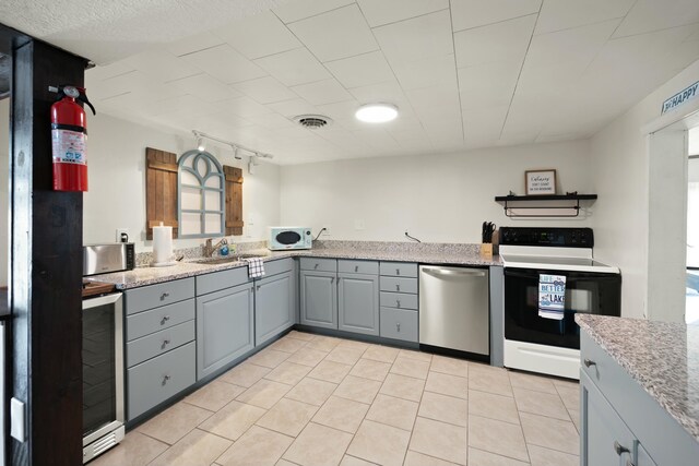 kitchen with light tile patterned floors, baseboards, freestanding refrigerator, gray cabinets, and light countertops