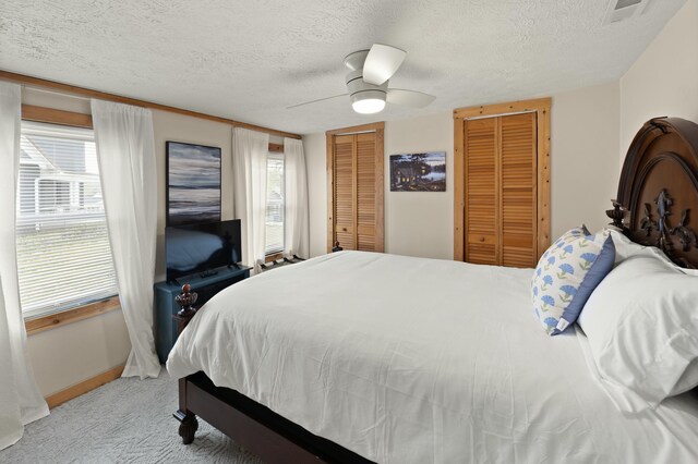 bedroom featuring visible vents, ceiling fan, light carpet, and a textured ceiling