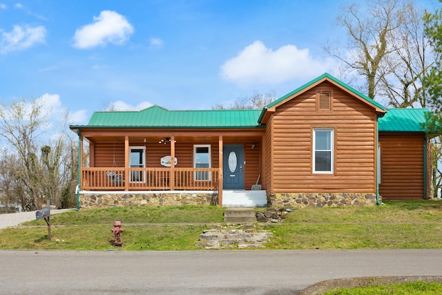 view of front of home featuring covered porch, metal roof, log veneer siding, and a front yard