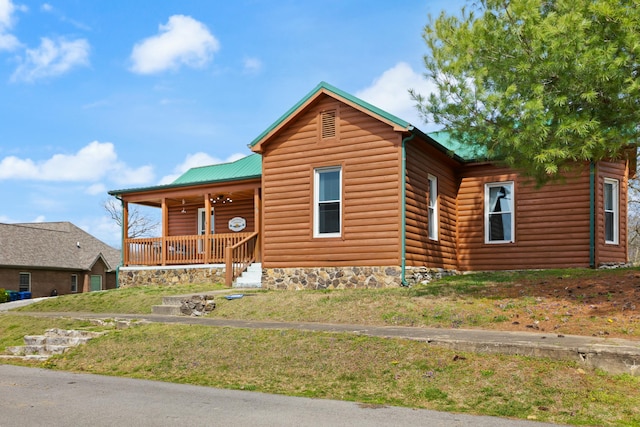 view of front of house with metal roof, a porch, and log veneer siding