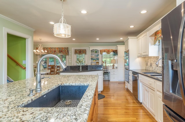 kitchen featuring light stone countertops, stainless steel appliances, white cabinetry, and sink