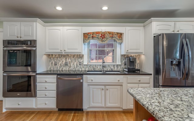 kitchen featuring white cabinets, appliances with stainless steel finishes, dark stone counters, and sink