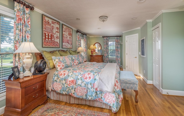 bedroom with crown molding, a textured ceiling, and light wood-type flooring