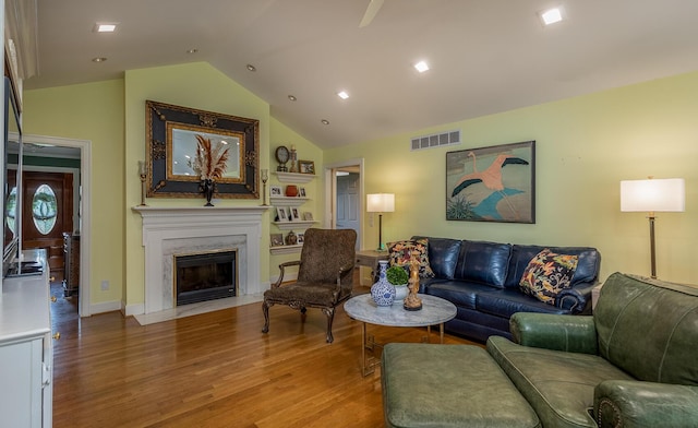 living room with lofted ceiling, a premium fireplace, and light hardwood / wood-style flooring