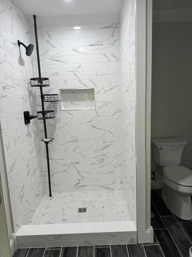 bathroom featuring tiled shower and toilet