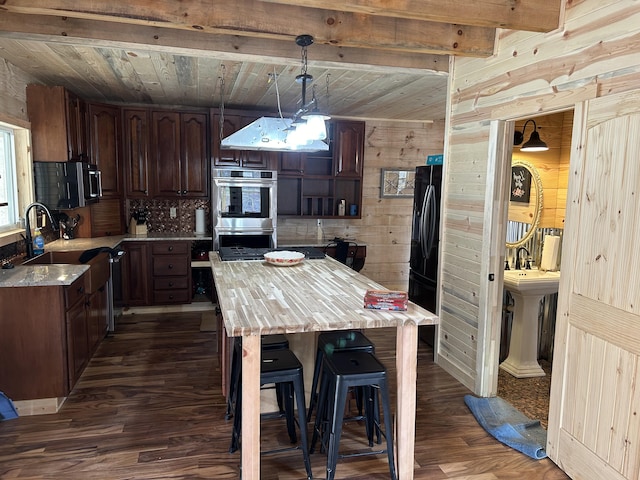 kitchen with wooden ceiling, wooden walls, stainless steel appliances, light countertops, and dark wood-style floors