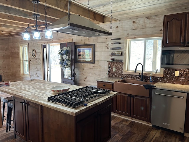 kitchen featuring wooden counters, backsplash, appliances with stainless steel finishes, dark wood-type flooring, and a sink