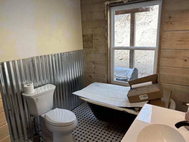 half bathroom featuring toilet and wooden walls