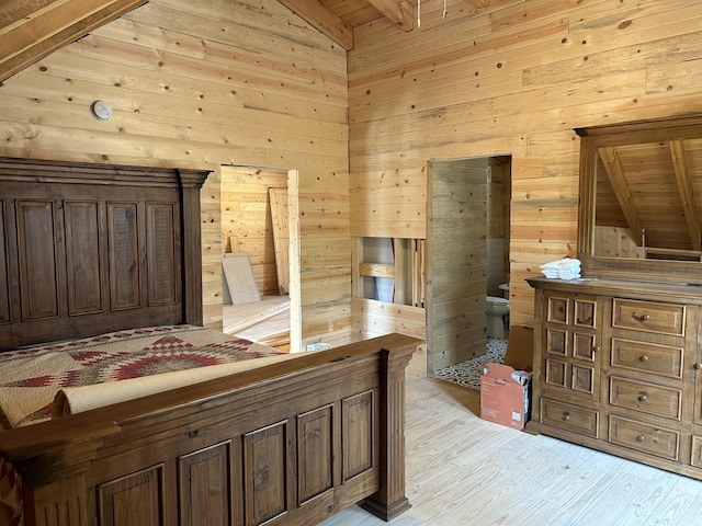 bedroom featuring lofted ceiling, light wood-style floors, and wooden walls