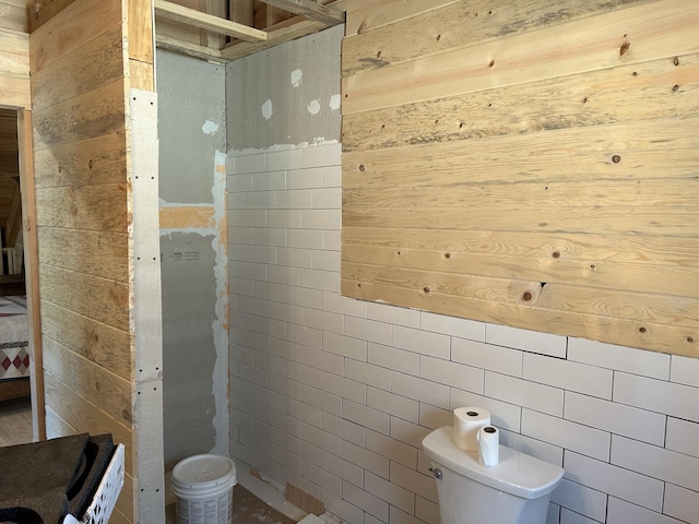 bathroom featuring toilet and wooden walls