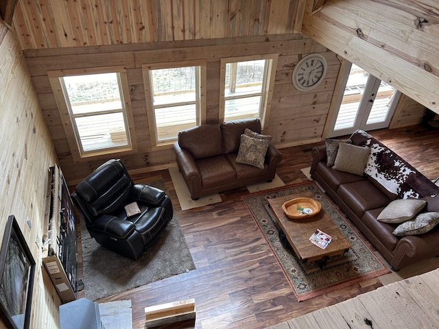 living area with lofted ceiling, wood finished floors, and wooden walls