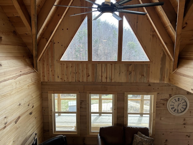 unfurnished living room featuring high vaulted ceiling, a ceiling fan, and wooden walls